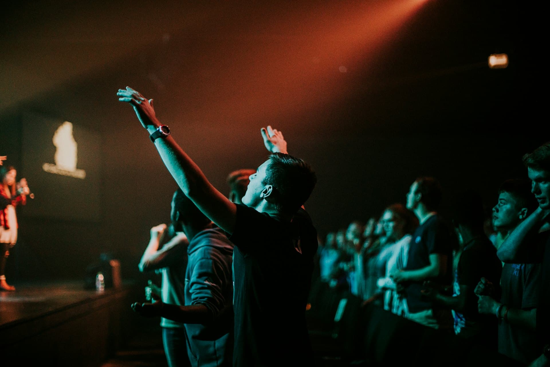Jongeren tijdens een worshipavond met opgeheven handen
